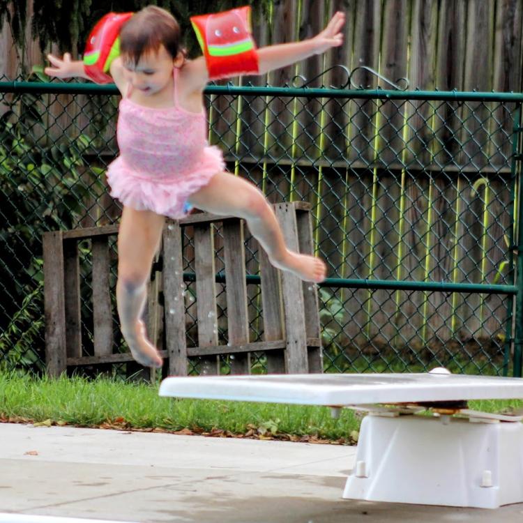 little girl jumps off diving board