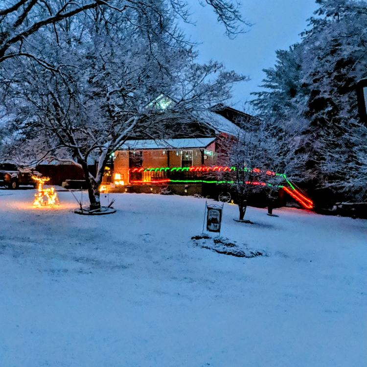 house with Christmas lights in snow