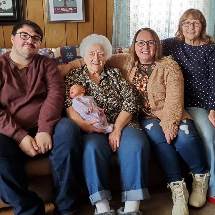 three women, a man, and a small baby on a couch