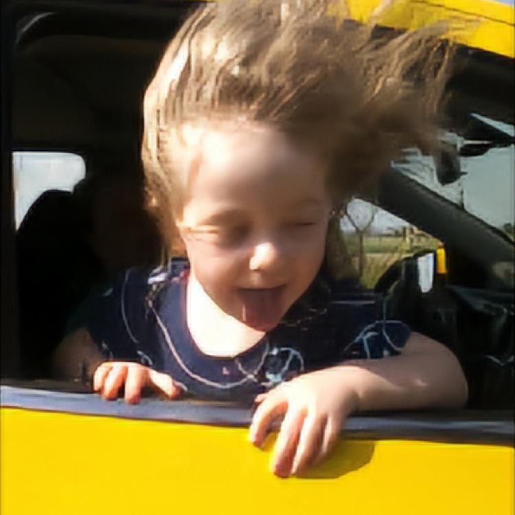 little girl with hair blowing in car window