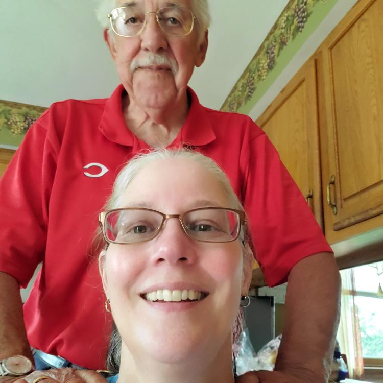 man in red shirt standing behind woman