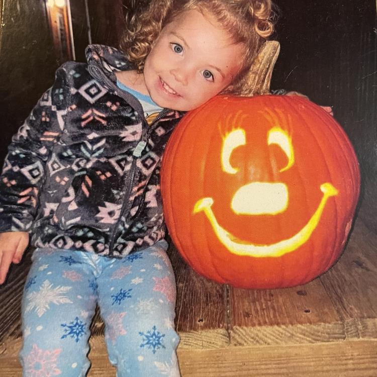 little girl hugging smiling jack-o-lantern