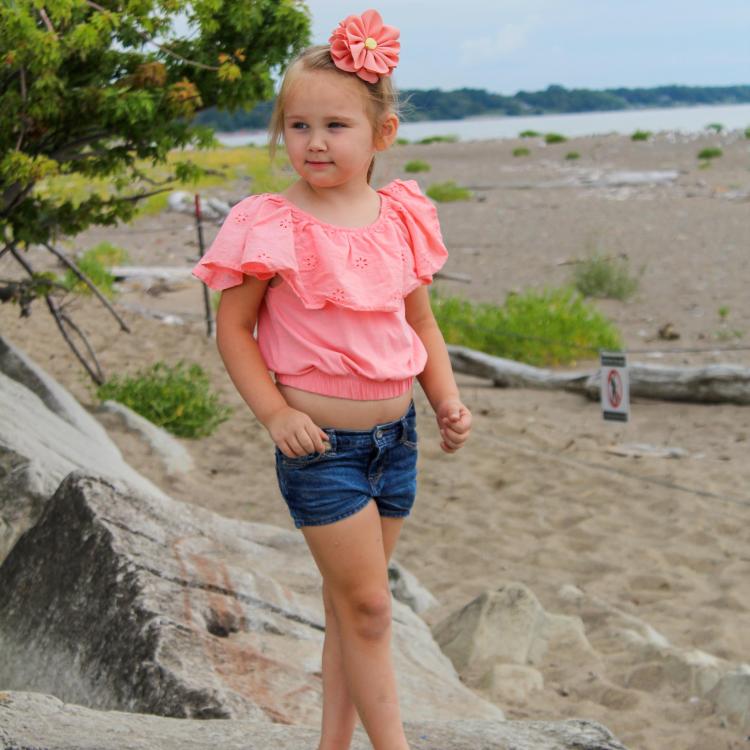 little girl on rocks by sandy beach