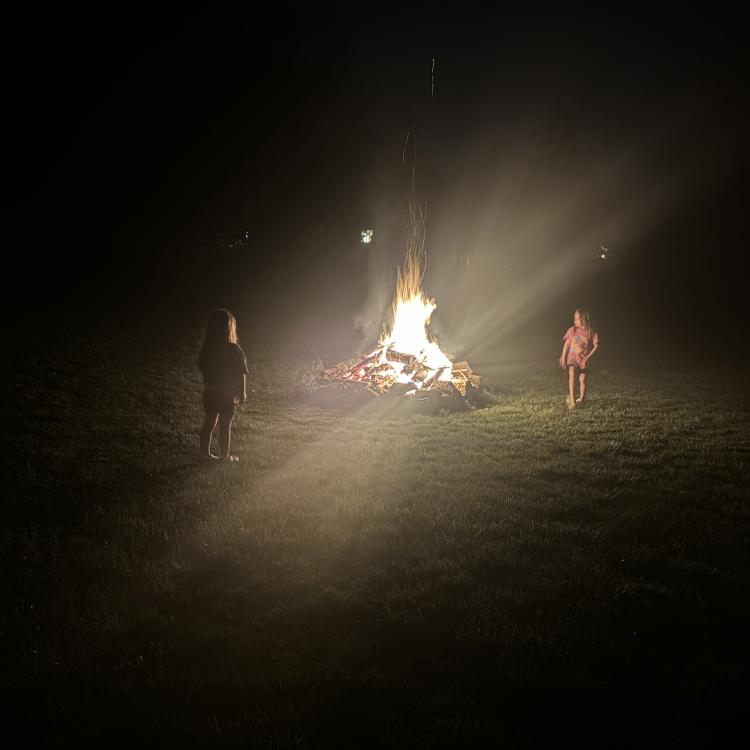 two girls standing in glow of campfire