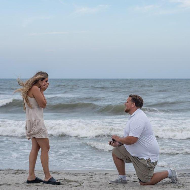 man on knee in front of woman on beach
