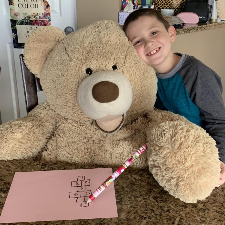 Little boy sitting next to giant stuffed bear