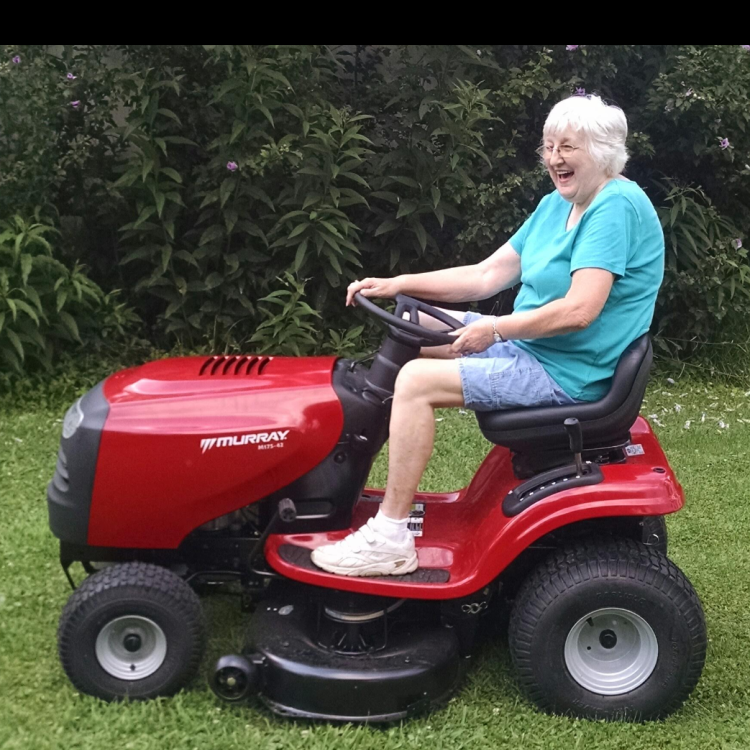 smiling woman on red riding mower