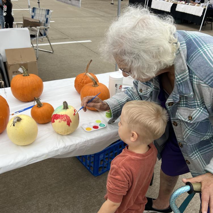 little boy and woman painting pumpkins