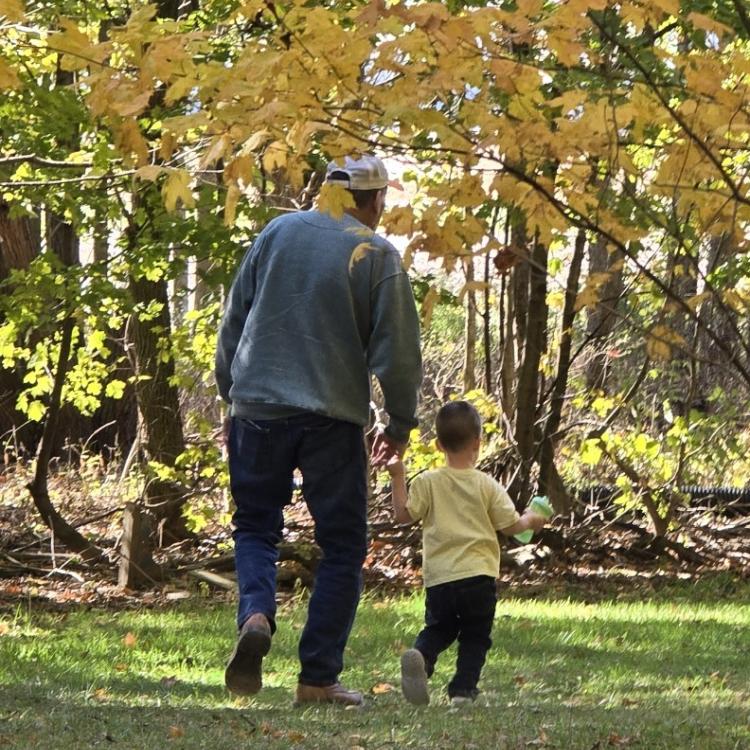 man and little boy walking by autumn trees
