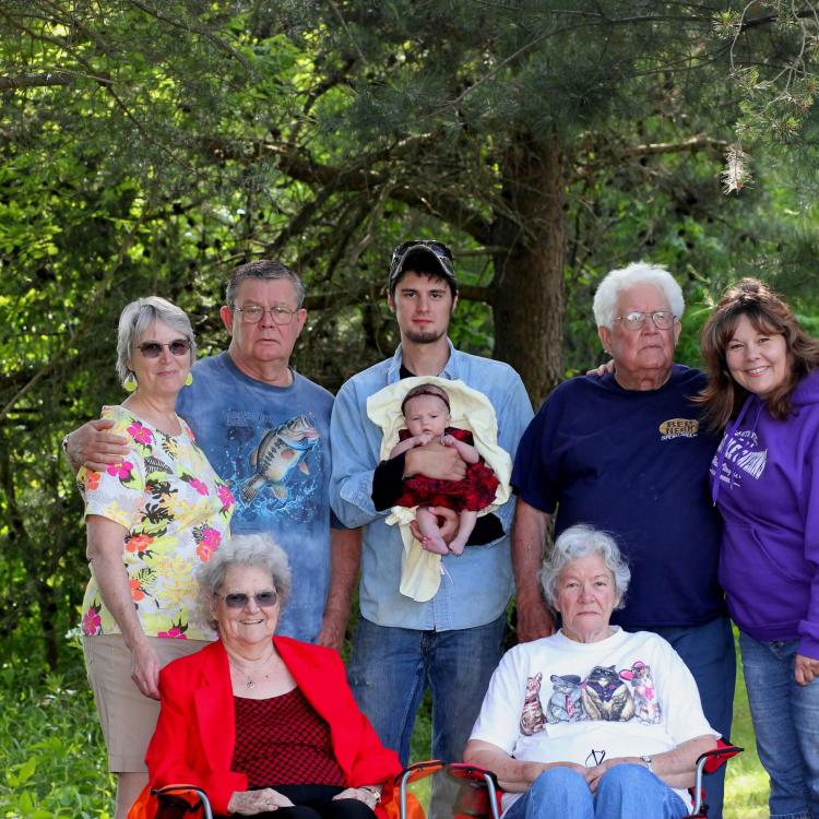 several generations pose in front of trees