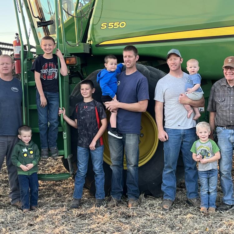 men and boys in front of green farm machinery