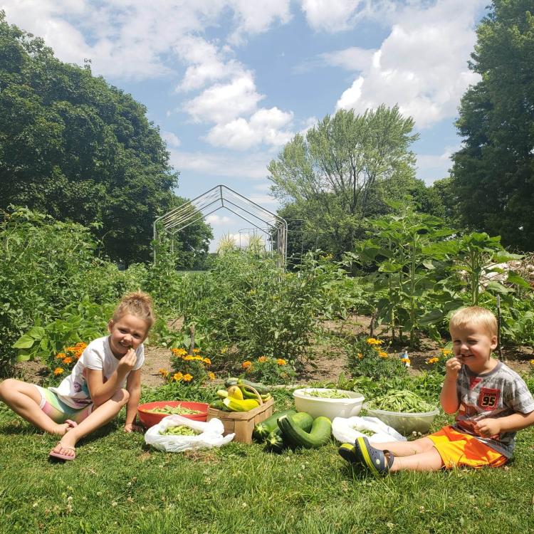 A boy and a girl sit in a sunny garden