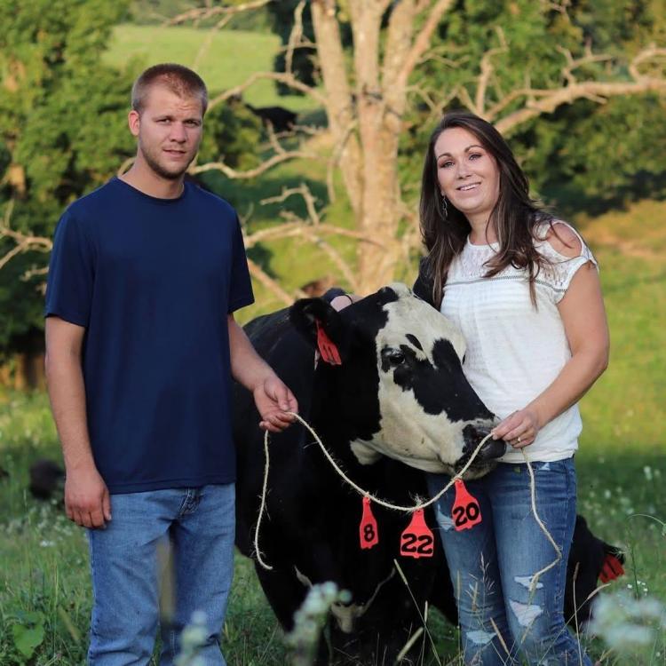smiling man and woman with a cow