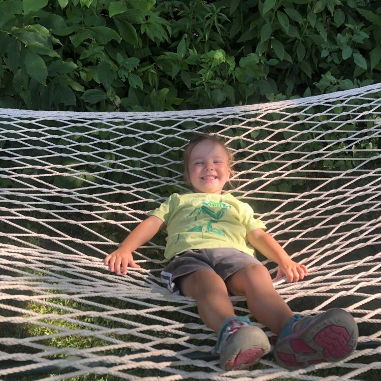 smiling girl reclines on hammock