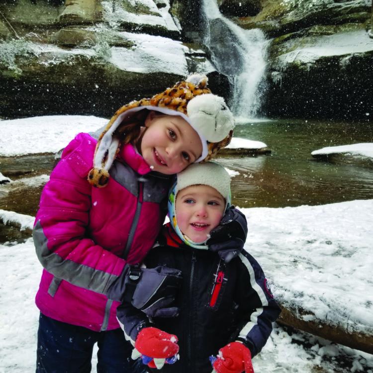 two kids in front of waterfall in winter