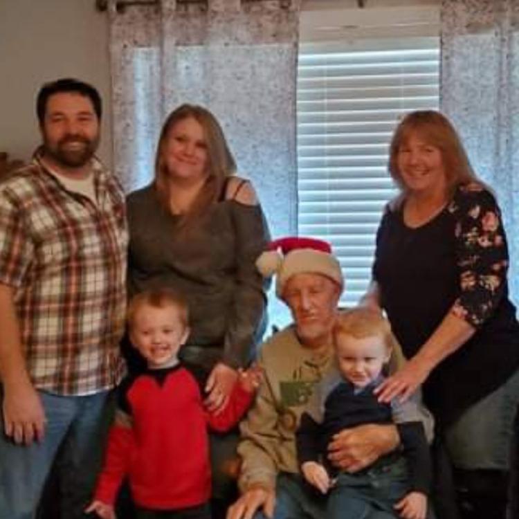 two men, two women, and two children pose in front of a window