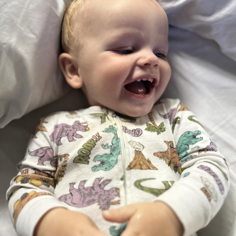 smiling baby in dinosaur pajamas