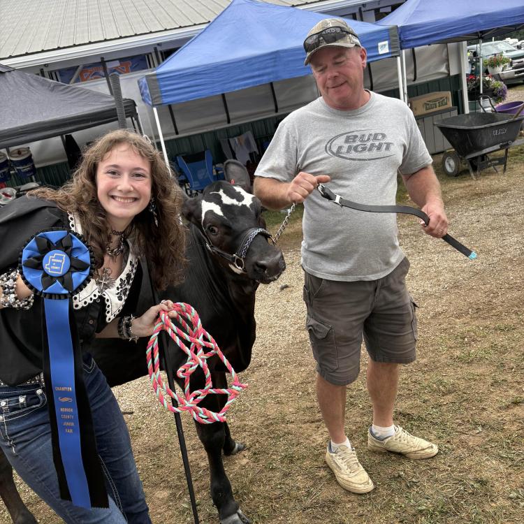 girl holding ribbon and man with cow
