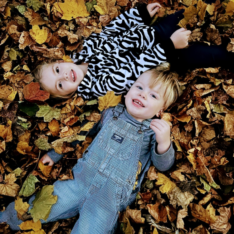 two children lying in leaves