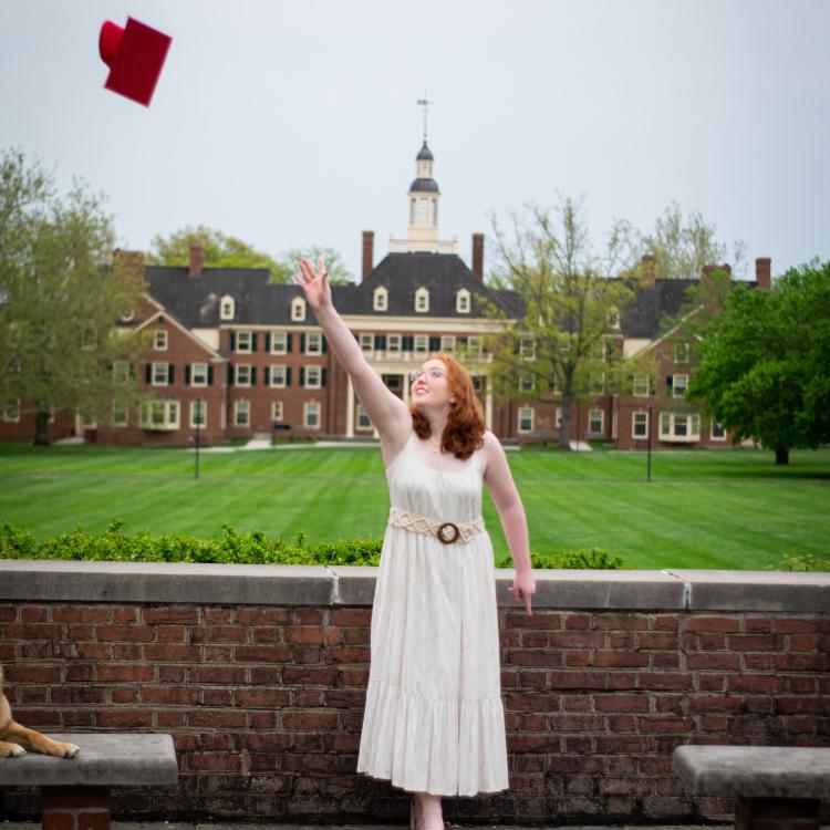 young woman tossing red graduation cap