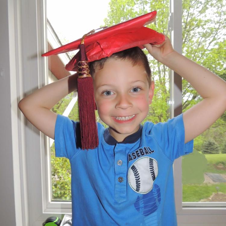 little boy in red graduation cap