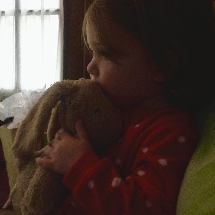 little girl in Christmas pajamas with stuffed rabbit