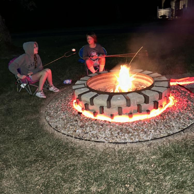 two children roasting marshmallows over fire pit