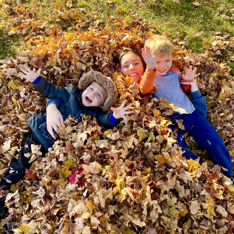 three people in leaf pile