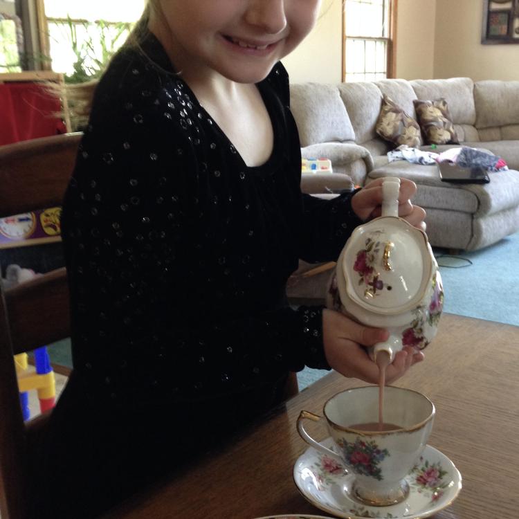 girl carefully pours tea from china teapot into teacup