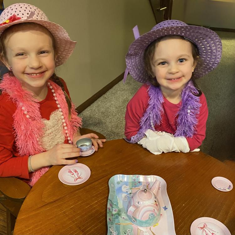 two little girls in hats having tea