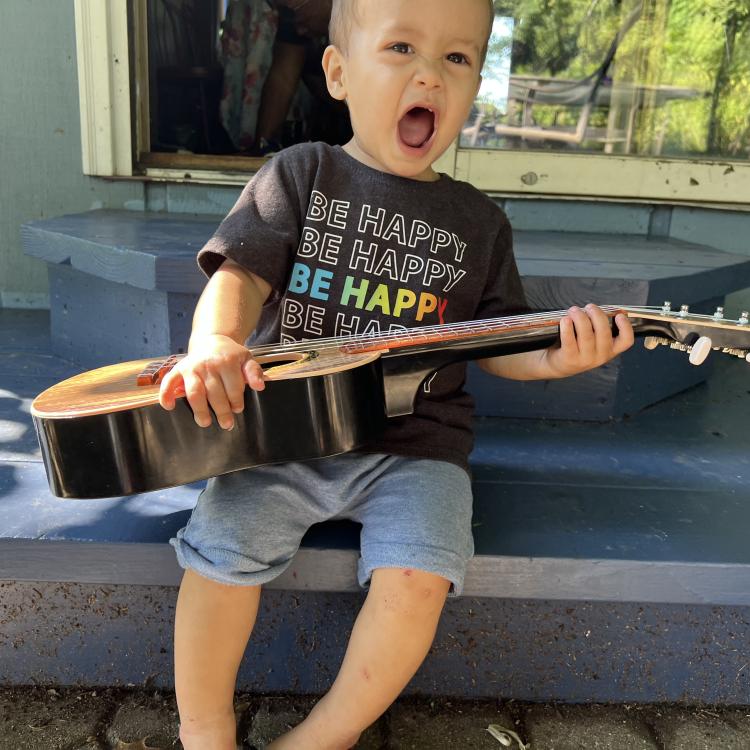 little bo on edge of porch, holding guitar and singing