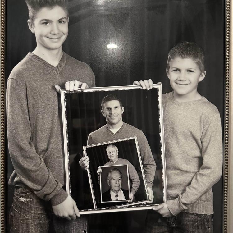 two boys holding a photo of a man holding a photo of a man holding a photo of a man