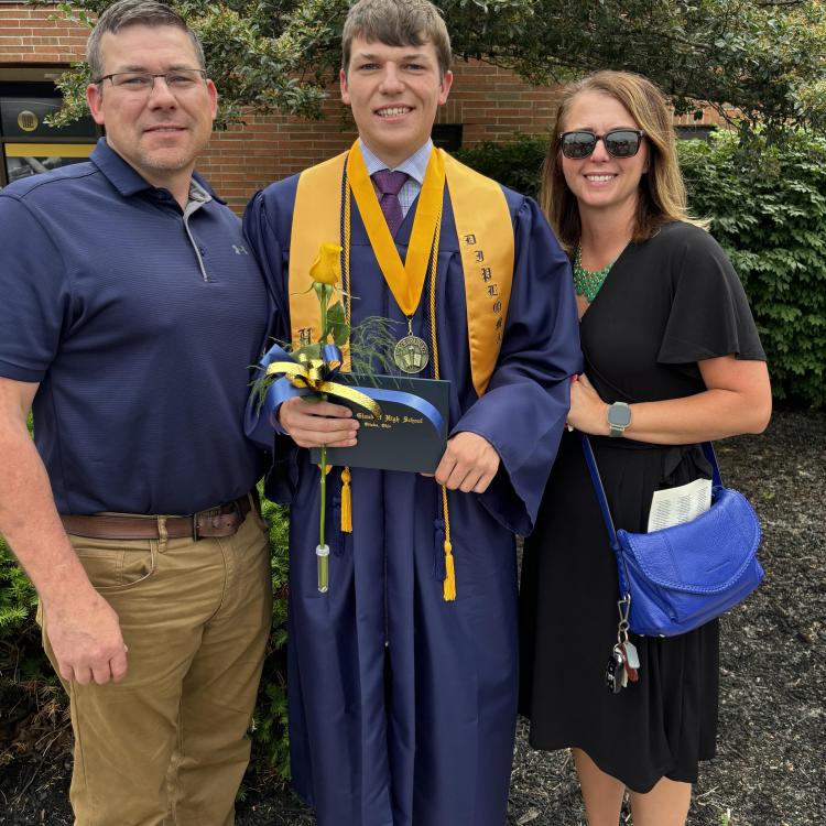 young man in blue graduation gown, between parents