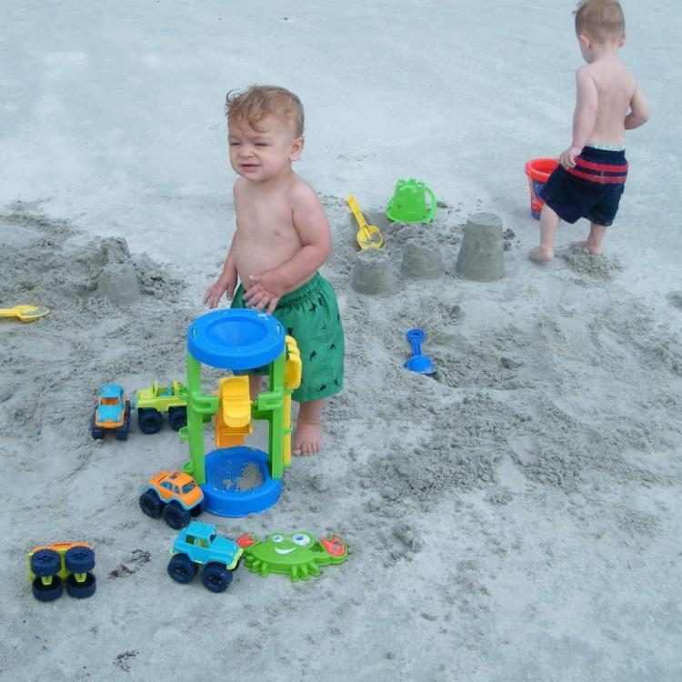 two little boys on beach with toy cars