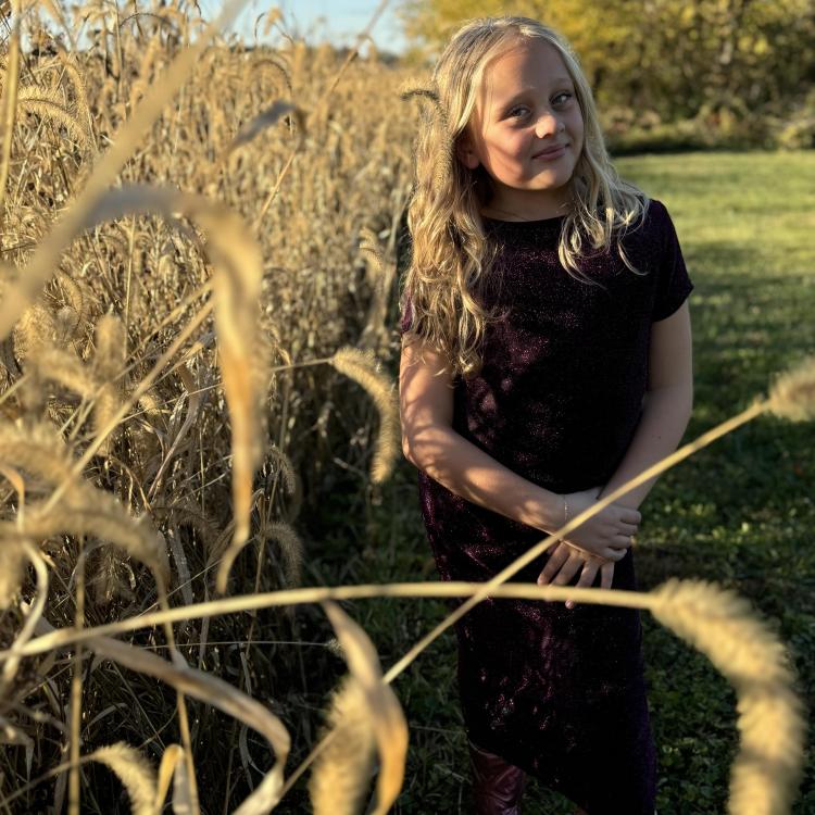 girl by cornfield with trees in background