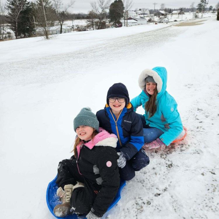 three kids on sled in snow