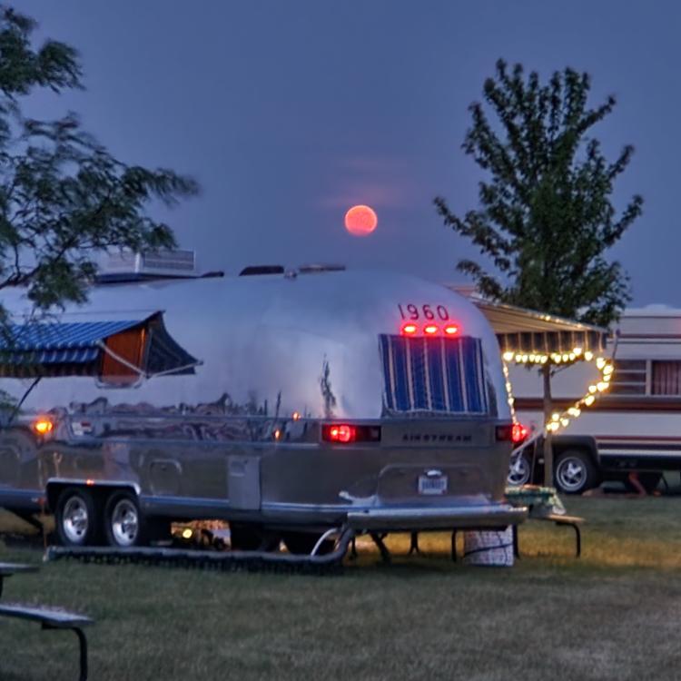 Shiny camper with pink moon in the distance.