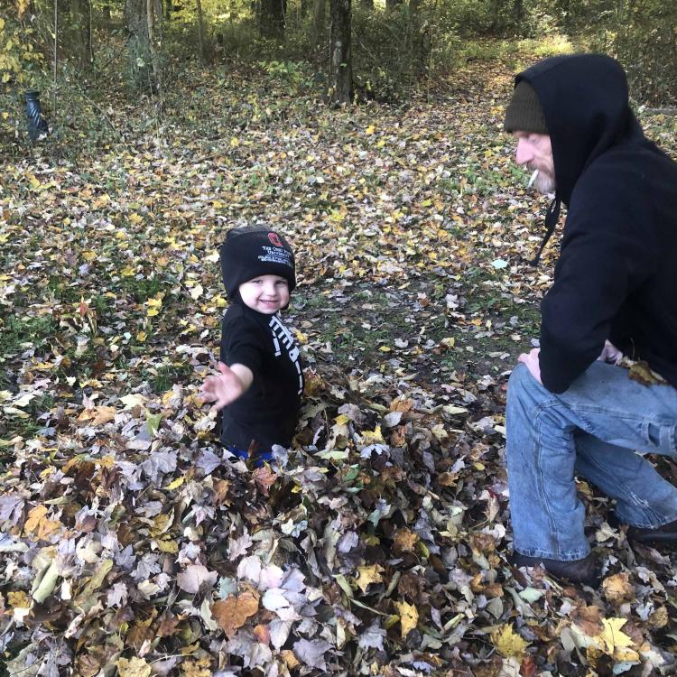 little boy with hat in leaf pile