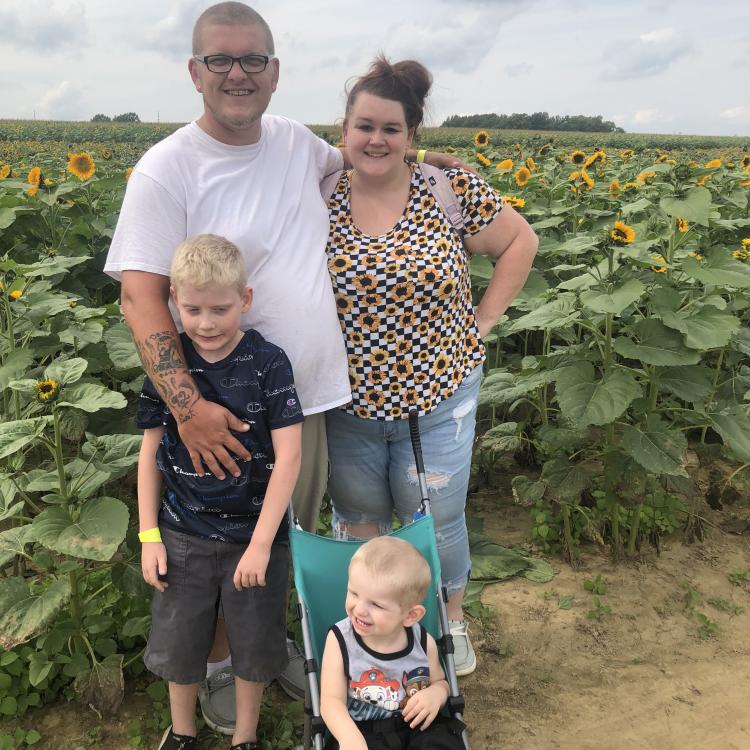 Man, woman, and two kids by a field of sunflowers