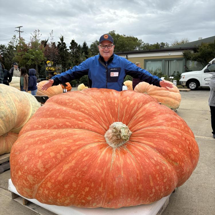 man standing behind enormous pumpkin