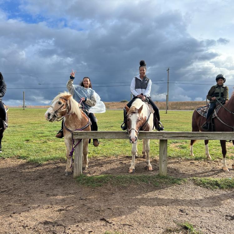 four people on horseback in front of cloudy skies