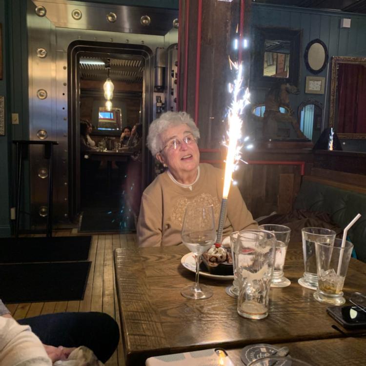 woman at table with cake topped with sparkler