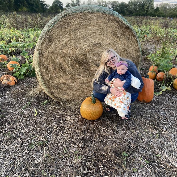 woman holding baby in pumpkin patch