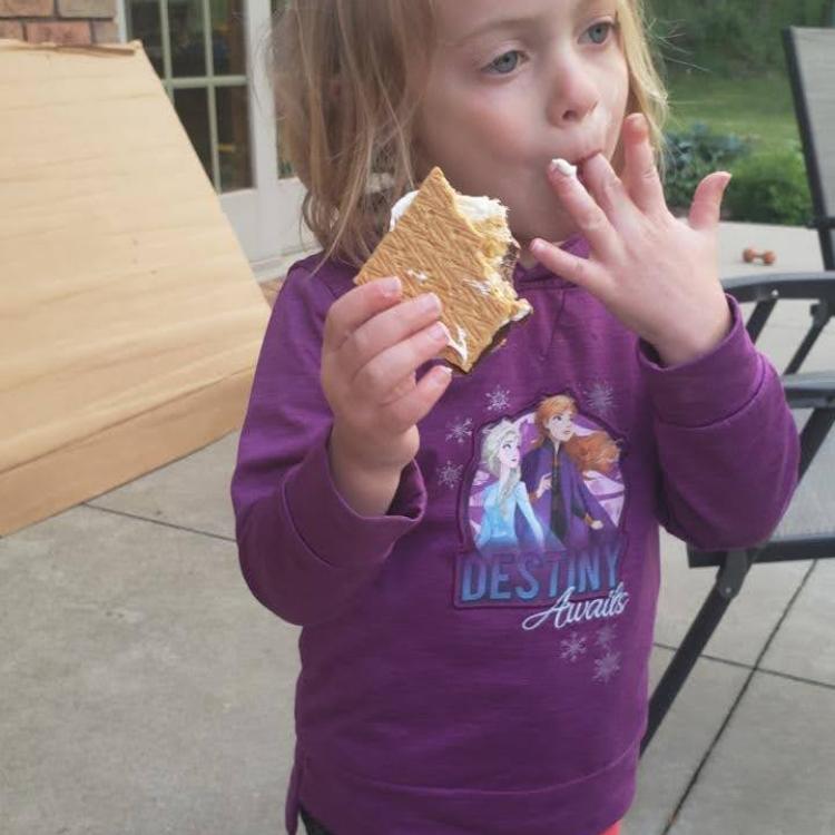 little girl licking s'more off her fingers