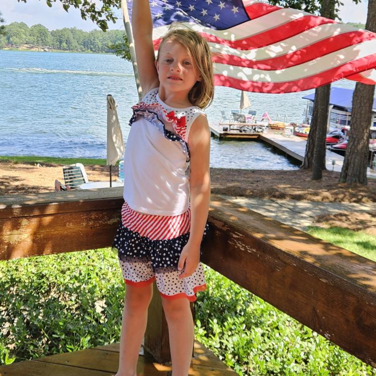 girl in red-white-and blue outfit holding American flag