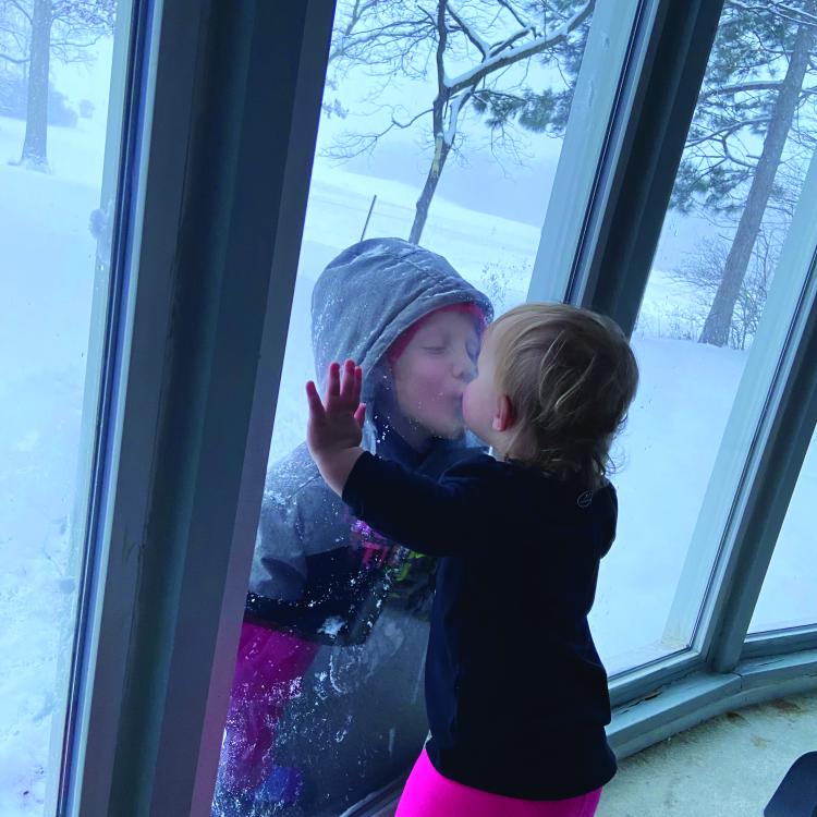 children kissing on either side of window