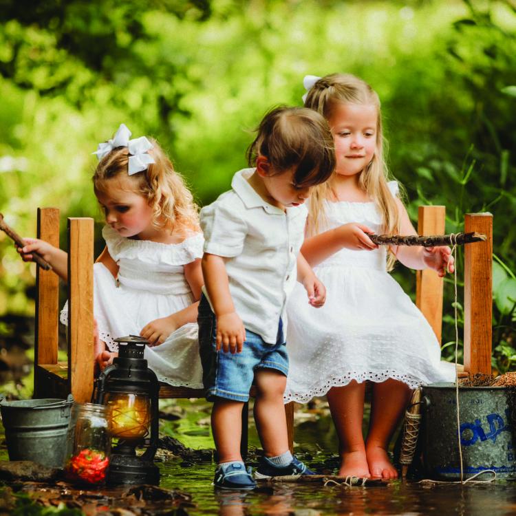 two little girls and a little boy on a bench