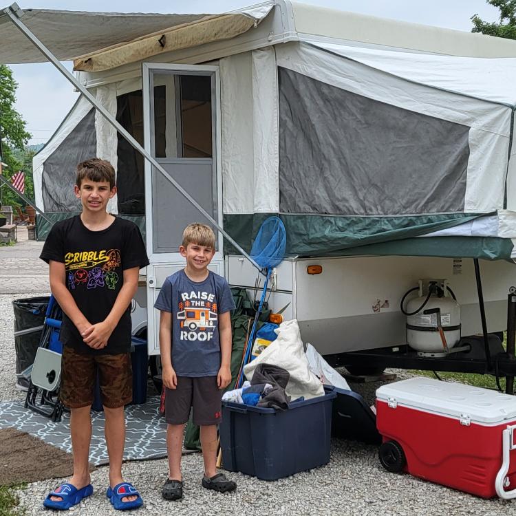 two boys standing in front of pop-up camper