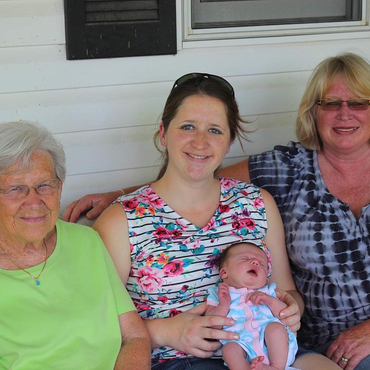 three women and a baby seated on a porch