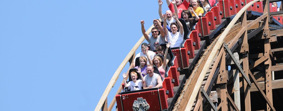 Riders of The Beast put their hands in the air as they start to descend a hill on the coaster